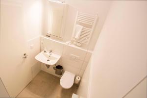 a white bathroom with a toilet and a sink at NEU: Zentral gelegene, stilvoll eingerichtete Zimmer mit eigener Teeküche in Nuremberg