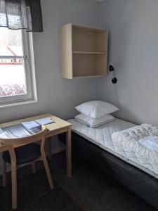 Habitación pequeña con cama, escritorio y ventana. en Valla Folkhögskola, en Linköping