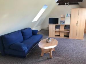 un soggiorno con divano blu e tavolo di Gemütliche Ferienwohnungen in Friedland Ortsteil Cosa a Friedland