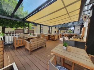 un restaurante con mesas y bancos de madera y una sombrilla grande en Landhotel Imhof, en Neuhof