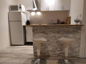 a kitchen with two white stools in front of a counter at Charmant studio au cœur de Cassis in Cassis