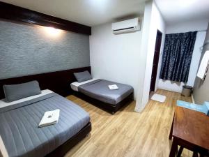 a room with two beds and a table and a desk at Hotel Musfa in Kota Bharu