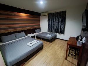 a bedroom with a bed and a desk and a bed and a window at Hotel Musfa in Kota Bharu
