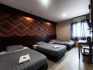 a room with three beds and a desk at Hotel Musfa in Kota Bharu