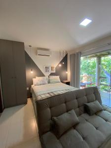 um quarto com uma cama grande e um sofá em Villas do Pratagy Temporada em Maceió