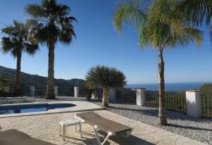 a patio with a bench and palm trees and the ocean at Stunning Villa near Velez-malaga in Arenas