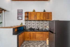 una cucina con mobili in legno e un frigorifero in acciaio inossidabile di The Secret Jungle Villas Berawa a Canggu Altre 21 foto