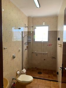 a bathroom with a shower with a toilet and a window at REFÚGIO DA SEREIA ARIEL in Mongaguá