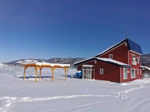 a red barn in the snow next to a building at House Of Joy Furano -15 mins to ski resort- in Furano