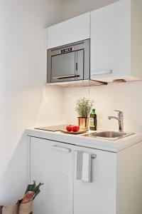 eine weiße Küche mit einer Spüle und einer Mikrowelle in der Unterkunft VISIONAPARTMENTS Binzmühlestrasse 46 - contactless check-in in Zürich