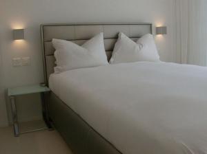 ein großes weißes Bett mit Kissen und einem Nachttisch in der Unterkunft VISIONAPARTMENTS Binzmühlestrasse 46 - contactless check-in in Zürich