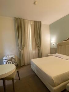 a hotel room with a bed and a table and a window at iH Hotels Bari Oriente in Bari