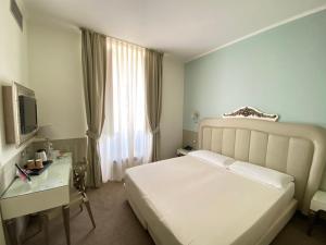 a bedroom with a bed and a desk and a television at iH Hotels Bari Oriente in Bari