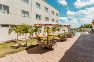 a hotel patio with tables and chairs and umbrellas at Go Inn Goiana by Atlantica Hotels in Goiana