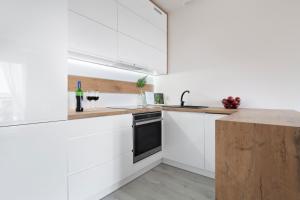 a kitchen with white cabinets and a black dishwasher at Elite Apartments Sunny in Gdańsk