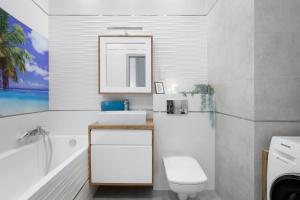 a bathroom with a sink and a toilet and a tub at Elite Apartments Sunny in Gdańsk