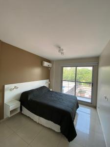 1 dormitorio con cama negra y ventana grande en 9 de Julio Park Suites en San Miguel de Tucumán