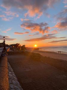 a sunset at the beach with people walking on the beach at Time Out in Exmouth