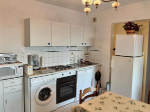 La cuisine est équipée de placards blancs et d'un réfrigérateur blanc. dans l'établissement Confortable appartement à 700m de la plage de Valras !, à Valras-Plage