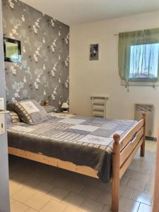 Ce lit se trouve dans une chambre dotée d'un mur à motifs floraux. dans l'établissement Confortable appartement à 700m de la plage de Valras !, à Valras-Plage