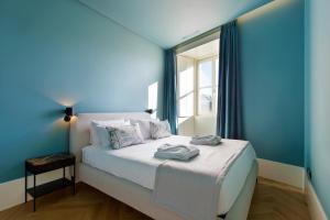 Dormitorio azul con cama y ventana en BOUTIQUE Rentals-Kinga’s Ribeira River great views, en Oporto