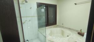 a bathroom with a tub and a glass shower at Casa nos Ingleses com piscina e jacuzzi in Florianópolis +27 photos