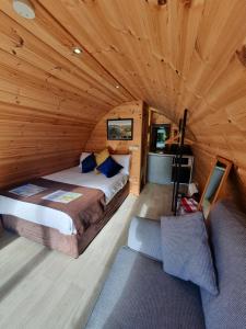 ein Schlafzimmer in einem Blockhaus mit einem Bett und einem Sofa in der Unterkunft Priory Glamping Pods and Guest accommodation in Killarney