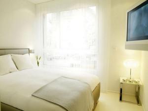 a white bedroom with a bed and a large window at VISIONAPARTMENTS Binzmühlestrasse 46 - contactless check-in in Zürich