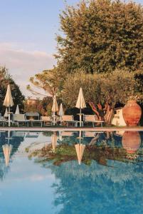 - une piscine d'eau avec des parasols et des chaises dans l'établissement Agriturismo Ca' Del Sol, à Lazise