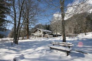 a wooden bench sitting in the snow in front of a house at Gasthaus-Pension Seeklause in Ramsau