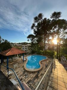 a large swimming pool with a sun setting in the background at Apartamento aconchegante em condomínio encantador. in Lambari