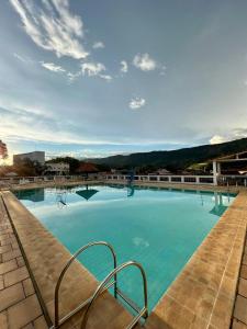 a large swimming pool with blue water at Apartamento aconchegante em condomínio encantador. in Lambari