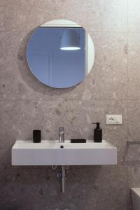 ein Badezimmer mit einem weißen Waschbecken und einem Spiegel in der Unterkunft whiterooms in Cesena