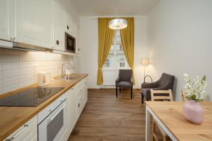 a kitchen with white cabinets and a table and chairs at Unesco Prague Apartments in Prague