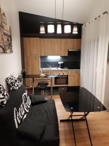 uma sala de estar com um sofá preto e uma mesa em Appartement de charme DISNEYLAND PARIS - Nidouest em Chanteloup En Brie