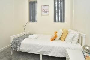 una camera da letto con un letto bianco e cuscini sopra di Townhouse @ Hall O Shaw Street Crewe a Crewe