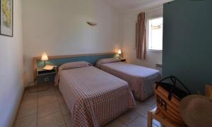 een kamer met twee bedden, een tafel en een raam bij Résidence les chênes in Borgo