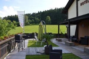 a patio with a table and chairs and a field at Hotel Gassbachtal in Grasellenbach