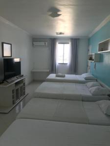 a room with three beds and a tv and a window at Hotel Pousada Irmaos Freyhardt in Rio de Janeiro