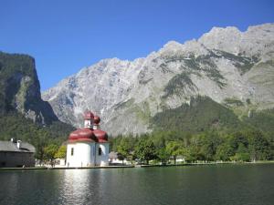 a building in the middle of a lake with a mountain at Königliche Villa - Turmappartement in Berchtesgaden +6 photos