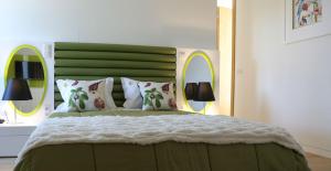ペニャフィエルにあるHotel Rural Quinta das Quintãesのベッドルーム1室(大きな緑色のベッド1台、鏡2つ付)