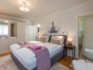 a bedroom with a large white bed with a pinkvisorvisorvisorvisor at Landhaus Central in Söll +17 photos