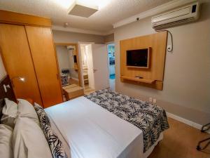 a hotel room with a bed and a television at Manhattan Porto Alegre by Mercure in Porto Alegre
