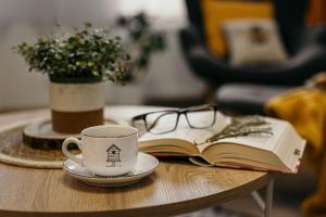 a cup of coffee and a book on a table at Apartament Miodownik in Międzylesie
