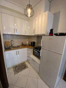 a kitchen with white cabinets and a white refrigerator at cozy apartment in Volos