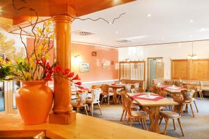 un restaurante con mesas y sillas y un jarrón con flores en Hotel "Zum Einsiedler", en Deutschneudorf