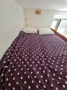 a purple bed with white polka dot sheets and pillows at Le Français, studio au calme proche de la gare in Besançon