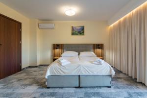 a bedroom with a large bed with white sheets at Hotel Perła Dunajca in Czarny Dunajec