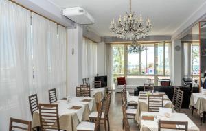 a restaurant with white tables and chairs and a chandelier at Hotel Los Angeles - Fronte mare in Riccione