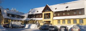 a snow covered building with cars parked in front of it at Hotel "Zum Einsiedler" in Deutschneudorf